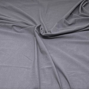 May include: A close-up of a smooth, grey fabric with a soft, wrinkled texture.