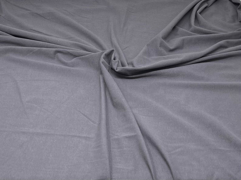 May include: A close-up of a smooth, grey fabric with a soft, wrinkled texture.