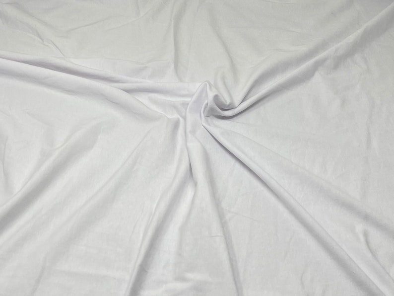 May include: White fabric with soft folds and wrinkles. The fabric is smooth and has a subtle sheen.