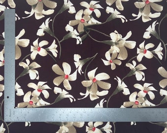 May include: A brown fabric with a white and beige floral pattern. The flowers are stylized and have red centers.