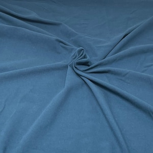 May include: A close-up of a smooth, blue fabric with a soft, wrinkled texture. The fabric is folded and draped, creating a sense of depth and dimension.