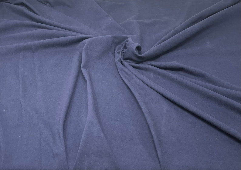 May include: A close-up of a smooth, dark blue fabric with a soft, wrinkled texture.