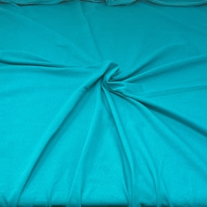 May include: A turquoise fabric backdrop with soft folds and wrinkles.