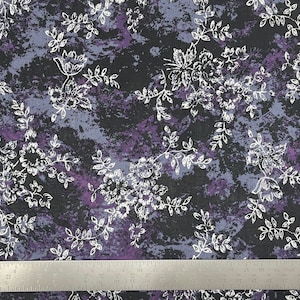 May include: A black fabric with a white floral pattern. The fabric has a mottled purple and blue background.