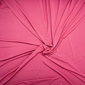 May include: A close-up of a pink fabric with a swirling pattern. The fabric is smooth and has a soft texture.