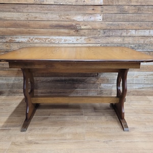 May include: A rectangular wooden table with a light brown finish. The table has curved legs and a lower support beam. The table is approximately 152 cm long and 76 cm wide.