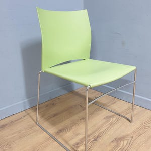 May include: A contemporary chair featuring a vibrant green seat and back. The chair has a curved back and a minimalist design. The frame is made of silver metal. Suitable for indoor use, the chair is a stylish addition.