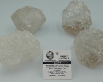 Może przedstawiać: Cztery przezroczyste kryształy kwarcu, z białą kartką, na której napisano "ENERGY CRYSTALS Χειροποίητο Κόσμημιο QUARTZ ATTRIBUTES THE ULTIMATE HEALER ENERGIC BOOSTER ARCHIVES KEEPER PROTECTS FROM RADIOLOGY PLANNING THERAPY: PHYSICAL-MENTAL MOLLIFIES THE PAIN HARMONIZES THE CHAKRAS"