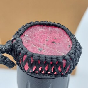 Puede incluir: Primer plano de una linterna negra y roja con un cordón trenzado negro. La linterna tiene una tapa de goma roja con un cordón trenzado negro.