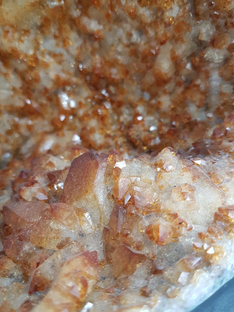 May include: Close-up of a geode with a cluster of small, clear, and amber-colored crystals. The crystals are arranged in a random pattern, creating a natural and organic look.