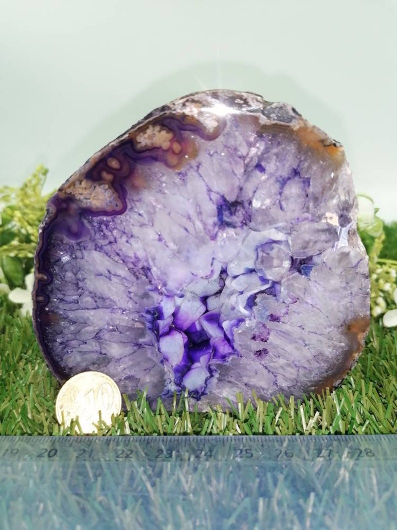 Puede incluir: Una gran rebanada de &aacute;gata p&uacute;rpura con una formaci&oacute;n de cristal blanco y p&uacute;rpura en el centro. La &aacute;gata tiene un di&aacute;metro de aproximadamente 18 cm.