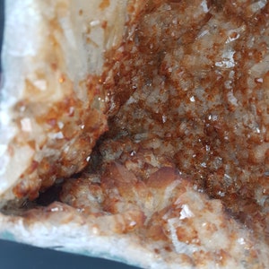 May include: A large, natural crystal geode with a white exterior and a brown, crystal-filled interior. The geode is a natural formation with a rough, textured surface.
