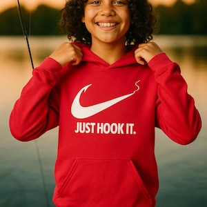 May include: A red hooded sweatshirt with a white graphic of a curved line and the words "JUST HOOK IT." The sweatshirt has a front pocket and a drawstring hood. The person wearing the sweatshirt is smiling.