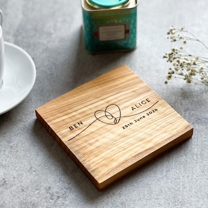 May include: A wooden coaster with the names "Ben" and "Alice" and the date "29th June 2024" engraved on it. The names are connected by a heart shape.