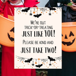 May include: Two children in Halloween costumes holding pumpkin buckets with a sign that reads "We're out trick-or-treating just like you! Please be kind and just take two!"