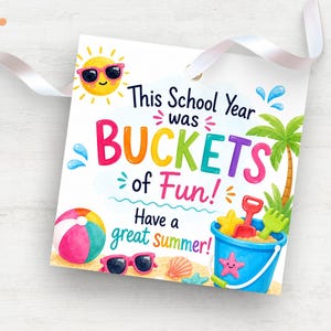 以下が含まれることがあります： 「This School Year was BUCKETS of Fun! Have a great summer!」のテキストが入った白いカードには、漫画の太陽、ビーチボール、サングラス、砂のおもちゃが入ったバケツが描かれています。白いリボンが付いています。