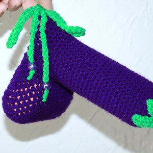 May include: A crocheted aubergine with green leaves and purple beads. The aubergine is made with a purple yarn and the leaves are made with a green yarn.