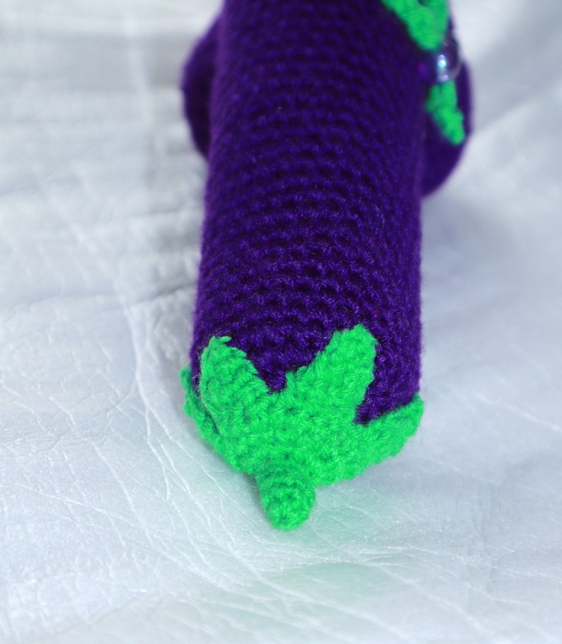 May include: Crocheted eggplant toy with a purple body and green leaves.