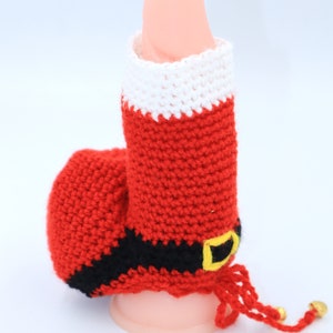 May include: A crocheted Santa Claus boot with a red and white striped pattern, a black belt with a gold buckle, and a red tassel.