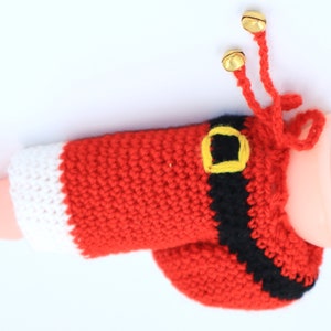May include: A red and white crocheted Santa Claus hat with a black belt and gold jingle bells.