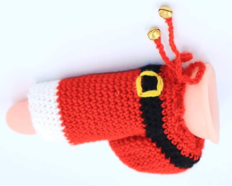 May include: A red and white crocheted Santa Claus hat with a black belt and gold jingle bells.