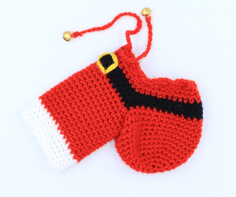 May include: Red and white crocheted Santa Claus stocking with a black belt and gold jingle bells.