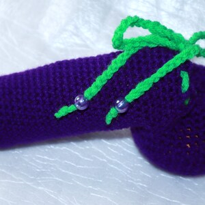 May include: A purple crocheted aubergine with green crocheted leaves and purple beads.