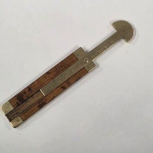 May include: A vintage folding ruler with a brass head and accents. The ruler is made of wood and brass, with measurements in inches. The ruler is brown and gold in color, and appears to be well-preserved.