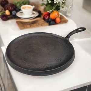 May include: A black cast iron pan with a handle. The pan is empty and has a slightly worn surface.
