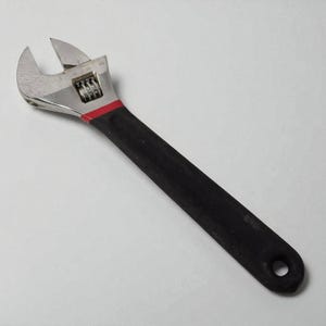 Adjustable wrench with black handle on a light gray background