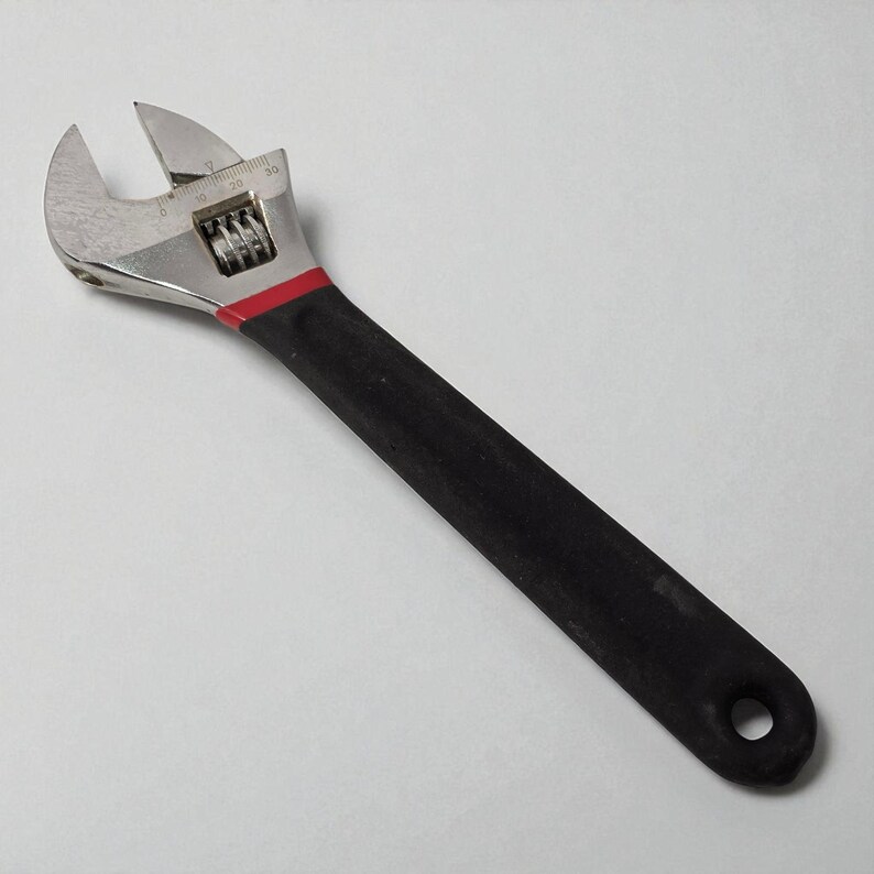 Adjustable wrench with black handle on a light gray background