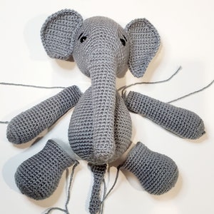 May include: A gray crocheted elephant toy in pieces. The body, head, ears, trunk, and legs are all separate pieces.