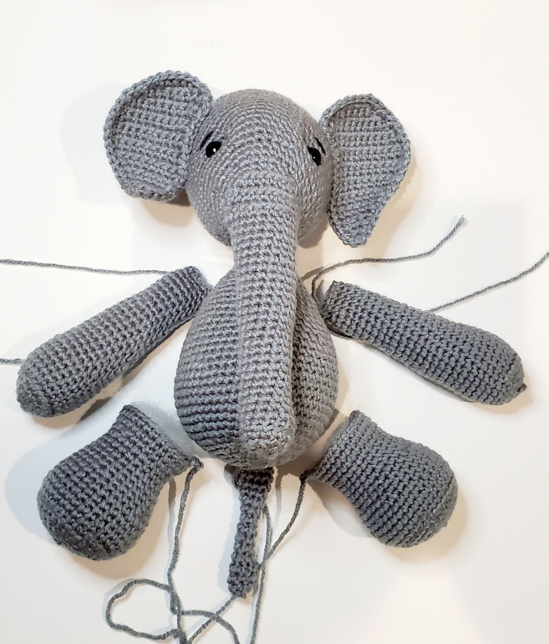 May include: A gray crocheted elephant toy in pieces. The body, head, ears, trunk, and legs are all separate pieces.