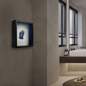 Pu&ograve; includere: Una cornice nera a scatola d'ombra con un passepartout bianco e un'immagine di silhouette blu all'interno. La cornice &egrave; appesa a una parete grigio chiaro.