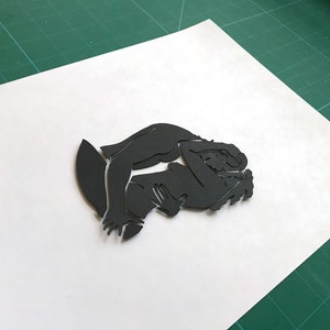 Pu&ograve; includere: Silhouette di due figure che si abbracciano, ritagliate in carta nera.
