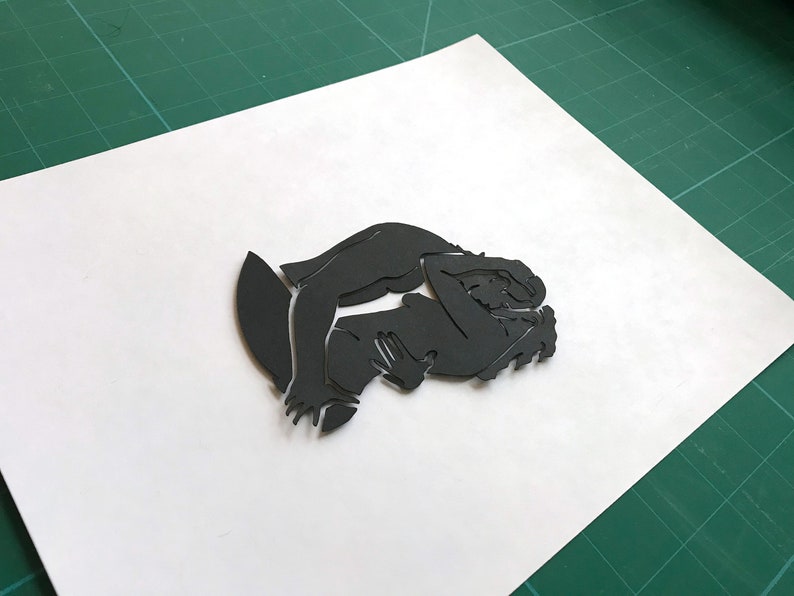Pu&ograve; includere: Silhouette di due figure che si abbracciano, ritagliate in carta nera.