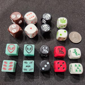 May include: A collection of novelty dice with various designs, including skulls, aliens, and cannabis leaves. The dice are in various colors, including brown, black, white, red, and green. A quarter is included for size comparison.