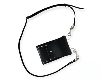 Può includere: Borsa a tracolla in pelle nera con finiture color argento. La borsa presenta una chiusura con patta ed è fissata con rivetti. È attaccata una lunga tracolla regolabile.