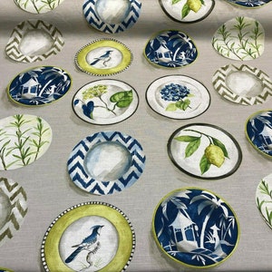 May include: A fabric with a repeating pattern of various plates with different designs. The plates feature blue, green, and yellow colors and depict images of birds, lemons, plants, and palm trees.