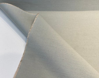 Könnte beinhalten: Nahaufnahme eines hellgrauen Stoffes mit einer dezenten Textur. Der Stoff ist in der Mitte gefaltet und zeigt die Kanten.