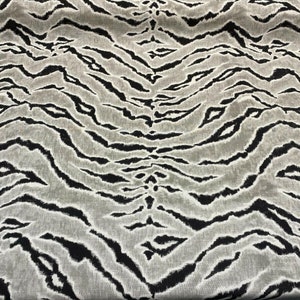 May include: Black and white tiger stripe fabric with a subtle sheen. The fabric has a woven texture and a soft, flowing drape.