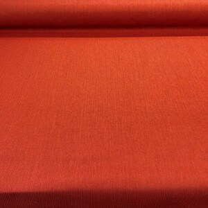 May include: A close-up of a roll of red fabric with a textured surface.