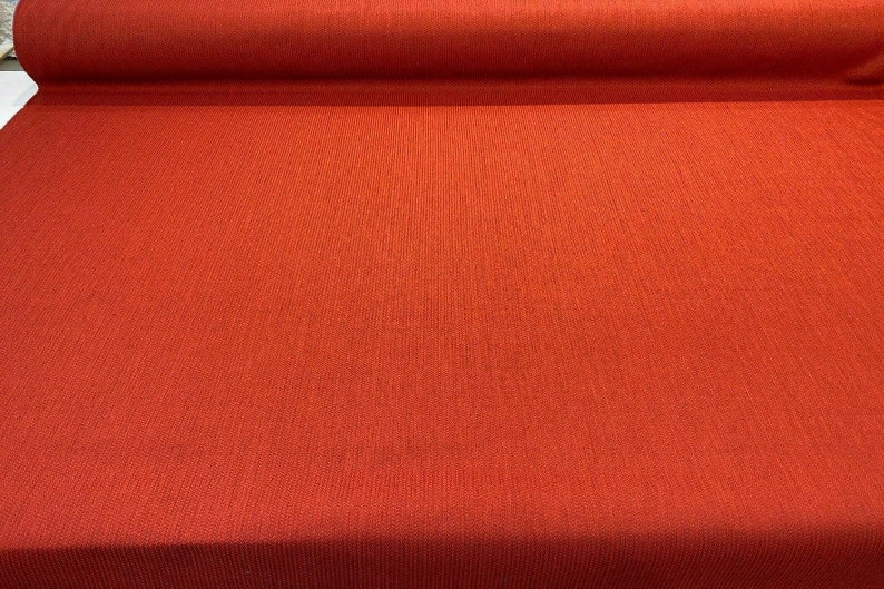 May include: A close-up of a roll of red fabric with a textured surface.