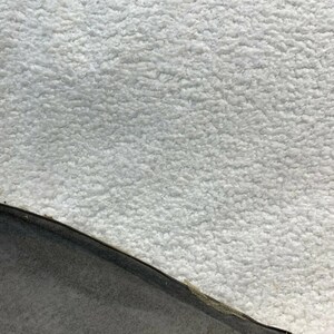May include: Close-up of a white fluffy fabric with a black fabric edge.