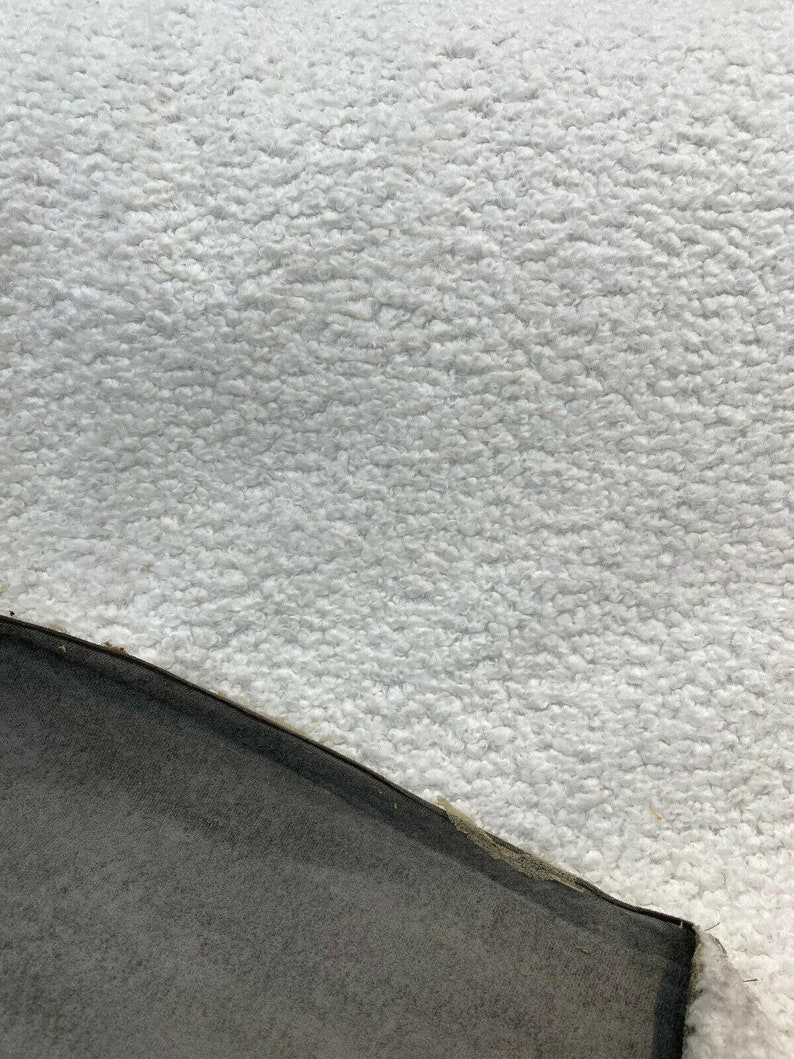May include: Close-up of a white fluffy fabric with a black fabric edge.