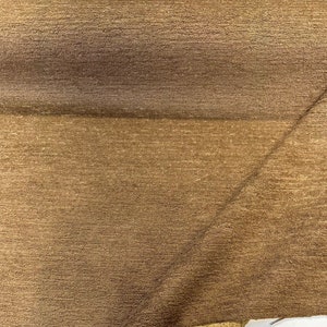 May include: Close-up of a brown fabric with a subtle shimmer. The fabric has a textured, woven appearance.