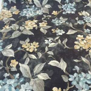 May include: Black fabric with a floral pattern featuring blue and yellow flowers. The flowers are painted in a watercolor style and have a vintage look.