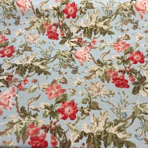 Puede incluir: Tela con diseño floral sobre fondo azul claro. El patrón presenta flores rojas y rosas, hojas verdes y detalles blancos. El diseño es un patrón repetitivo de elementos botánicos.