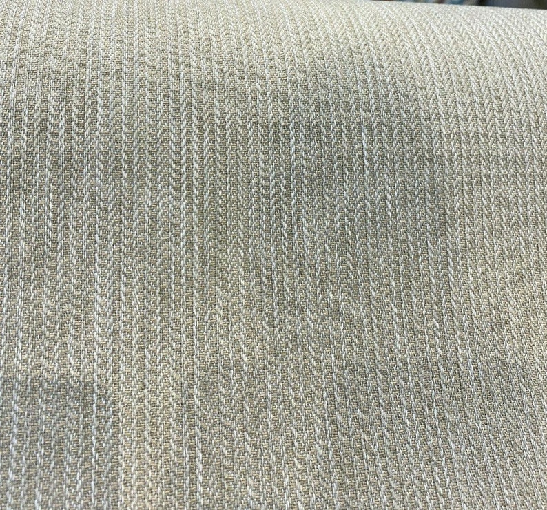 Puede incluir: Primer plano de una tela beige con un patr&oacute;n de espiga blanco. La tela tiene una textura sutil y una sensaci&oacute;n ligeramente rugosa.