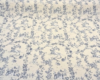 May include: Cream-colored fabric with a blue floral toile pattern. The design features detailed illustrations of flowers, vines, and pastoral scenes. The fabric is suitable for various craft and home decor projects.